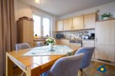 Haus Meeresrauschen Whg. 07 - Wohnzimmer mit Schlafcouch und offener Küche, Zugang zur Terrasse mit Meerblick