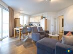 Haus Meeresrauschen Whg. 07 - Wohnbereich mit Esstisch, offener Küche und Zugang zur Terrasse mit Meerblick