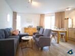 Haus Meeresrauschen Whg. 07 - Wohnbereich mit Esstisch, offener Küche und Zugang zur Terrasse mit Meerblick