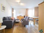 Haus Meeresrauschen Whg. 07 - Wohnbereich mit Esstisch, offener Küche und Zugang zur Terrasse mit Meerblick